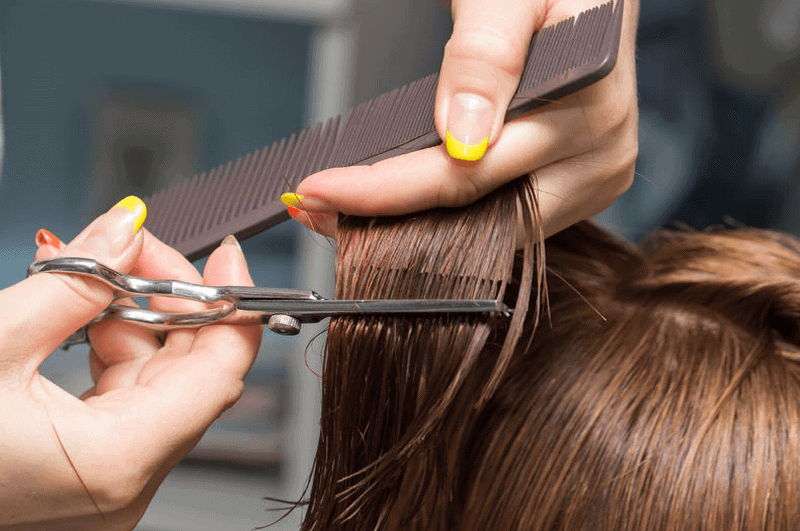 Friseur schneidet braunes Haar mit Schere und Kamm